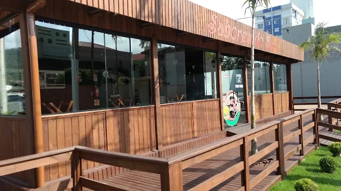 Varanda de madeira com mesas do Sabores do Sul, vista da entrada do salão